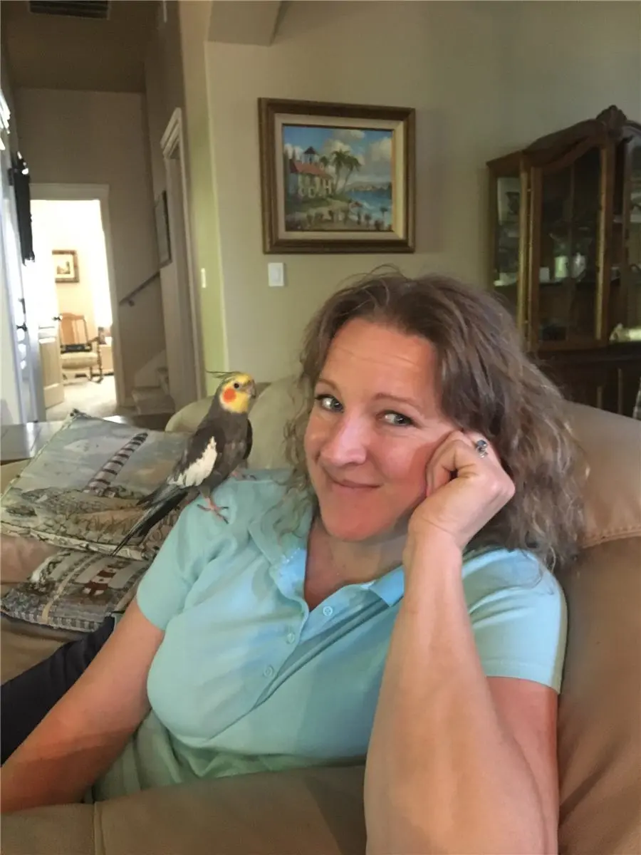 CarrieAnne at home with a cockatiel on her shoulder