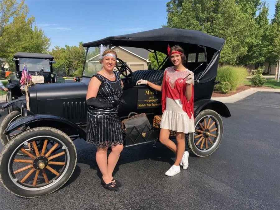 CarrieAnne and a friend in costume beside a vintage car